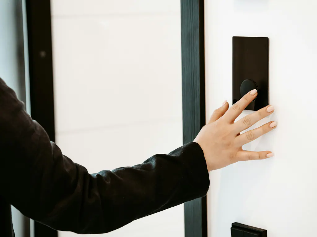 A hand pressing a minimal black wall control with a single dial