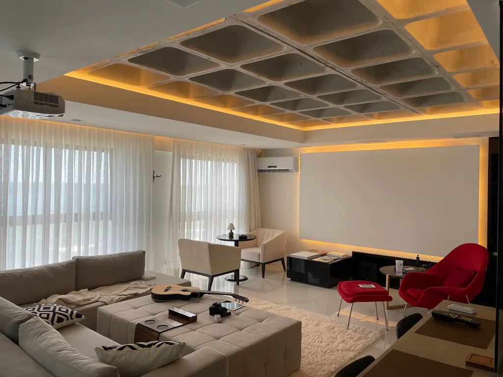 A media room with a ceiling projector, a screen wall and cove lighting in a coffered ceiling