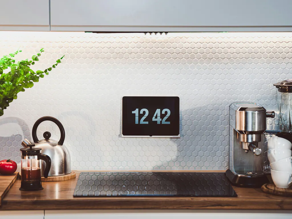 A kitchen backsplash with a small wall display beside a kettle and an espresso machine