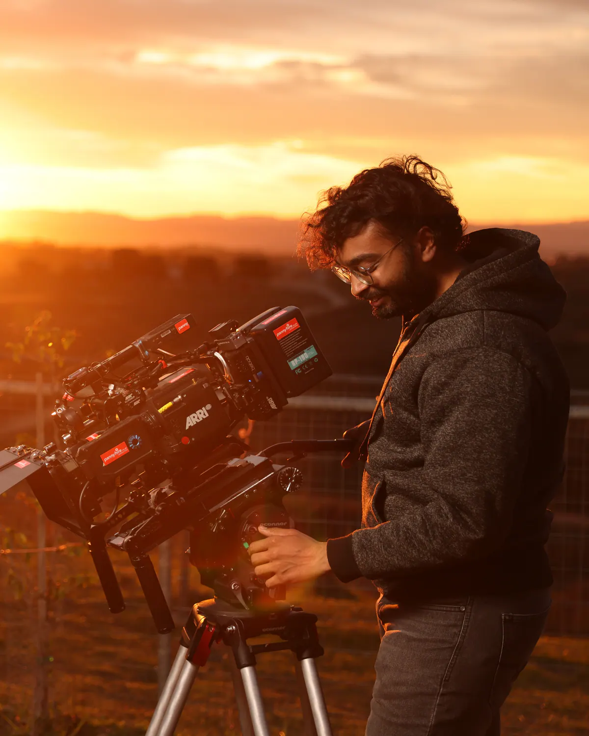 Siddharth Agrawal operating a cinema camera on a tripod at sunset